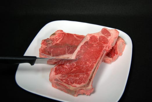 Fresh beef steaks on white plate.