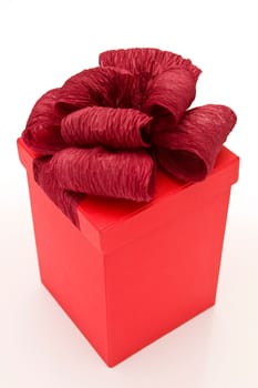 close up photo of red gift box tied with ribbon on white background