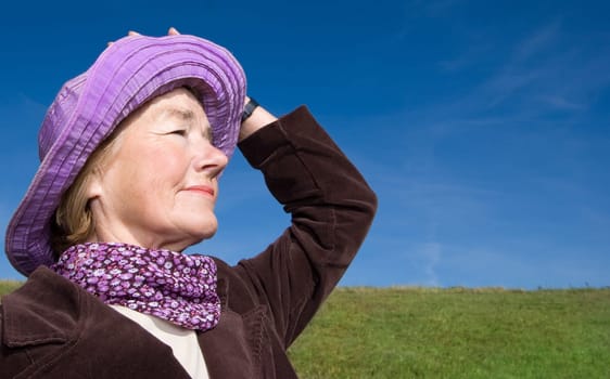 Happy mature woman on the meadow - in her favourite violet hat :-)