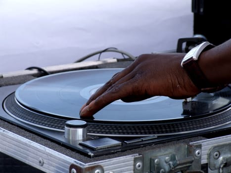 Close-up hotograph of a Black young adult male DJ's hand spinning vinyl record