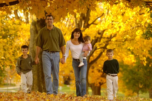 a happy family walking through colorful leaves