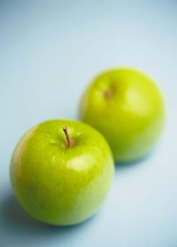 Two green apples (Granny smith), blue background