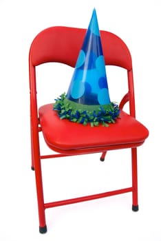 red child's chair with blue party hat: good for invitations . isolated on white