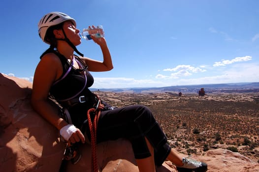 Female rock climber drinking water during a climb in Moab