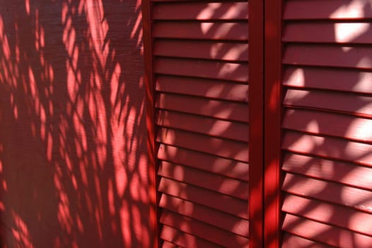 A deep red accordian door & wall with leaf sillhouettes.