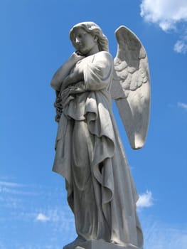 detail of winged angel statue against blue sky