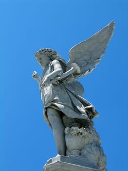 detail of winged angel statue against blue sky