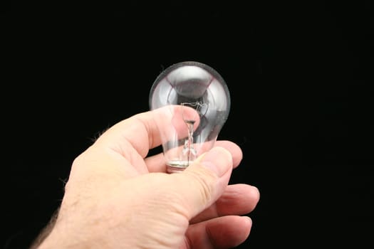 Hand holding clear light bulb with black background