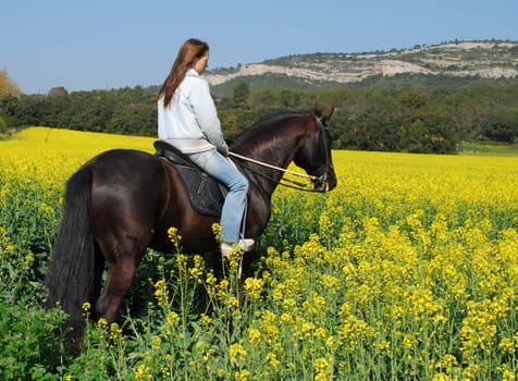 young teenager and her black horse in training of jumping competition