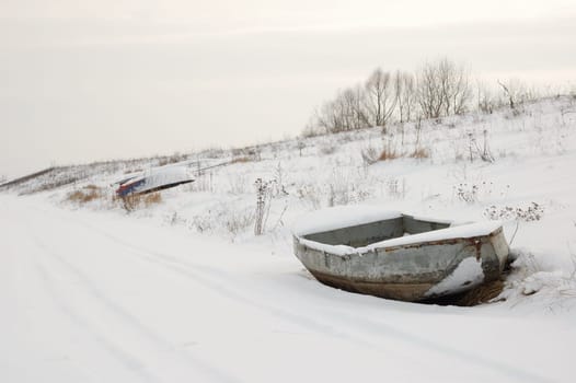 Boat in snow on shore, with visible trail