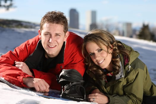 Happy couple lying on a snow with snowboard