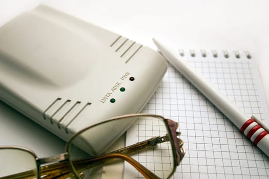 modem, notebook, pen and glasses on a light background