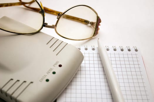 modem, notebook, pen and glasses on a light background