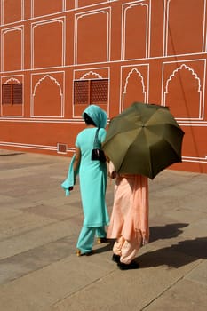 Traditional dressed Indian women walking through the Red Palace