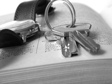 bunch of keys with watch on page of open book
