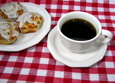 Sweet rolls and fresh coffee on a cheerful tablecloth.