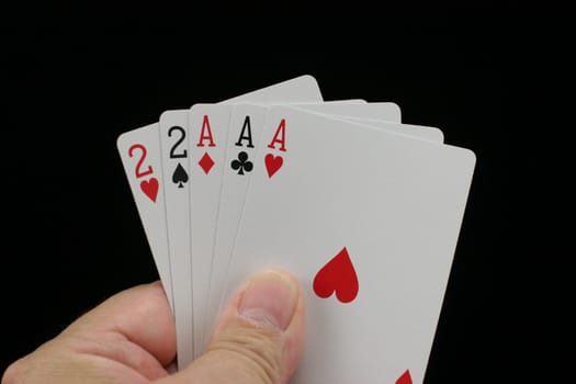 Hand holding full house poker hand with a black background.