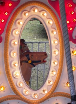 Oval mirror on a carousel reflecting a horse.