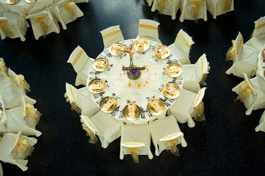 Table setting with golden plates and heart shapes on napkins plus scattered fresh rose petals for a wedding or romantic dinner event