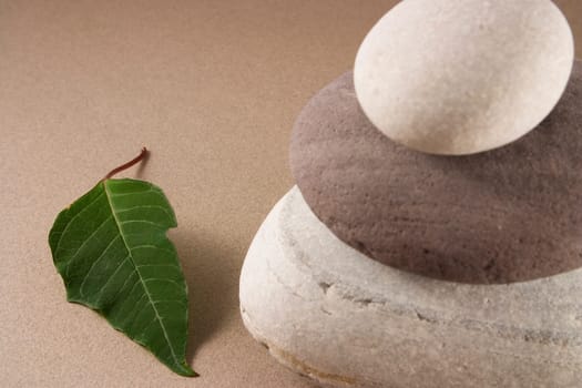 3 balanced pebbles with red and green leaves on a clear background