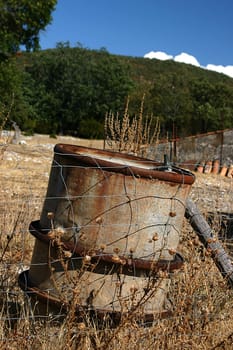 An old oil tank abandoned on the ground, leaned to the used up fencing. This is a clear sign of pollution the man should fight