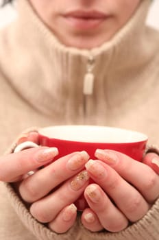 Red cup in female hands on a white background