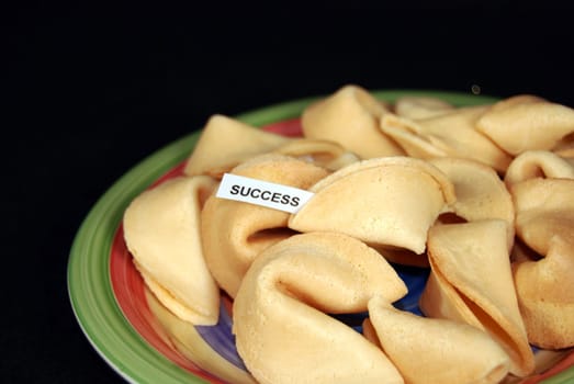 Plate of fortune cookies on black background.