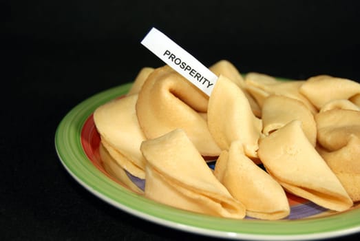 Plate of fortune cookies on black background.