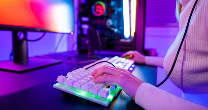 Close up gamer hands actively pushing buttons with colorful neon LED lights, woman guy typing on his gaming keyboard and mouse to playing some game in dark room using, E-sport concept