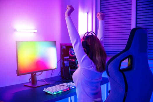 Winning Victory. Asian gamer playing online video game excited on desktop computer PC colorful neon LED lights, young woman in gaming headphones using computer she happy successful, E-Sport concept