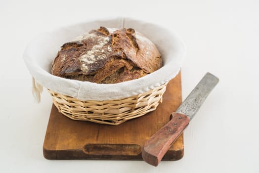 Rustic stone oven bread in a bread basket on a wooden board