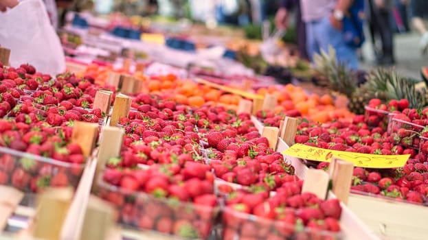 red strawberries at a weekly market. offered in trays, sweet and delicious.