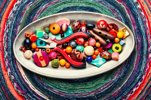A set of bright beads of different types for needlework. Beads on a variegated background.