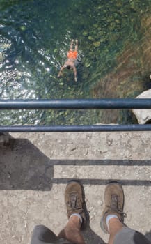 Trekker observing swimmer from bridge parapet. La Maquina Natural pool, Crystal-clear waters spot in the heart of La Vera County, Caceres, Extremadura, Spain