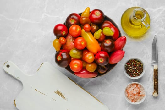 Top view of plate with colourful tomatoes, olive oil, salt and pepper. Simple vegetable salad.