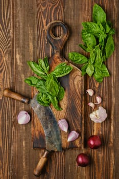 Basil, onion and garlic on wooden cutting board