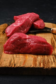 Closeup view of raw beef steak chopped on slices on shabby cutting board
