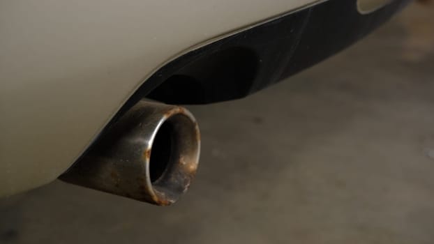 combustion fumes coming out of car exhaust pipe.