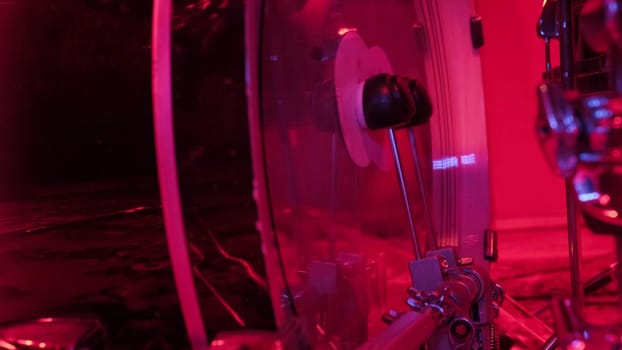 Drummer rehearsing on drum barrel before rock concert. Man recording music on drum set in studio in red light.