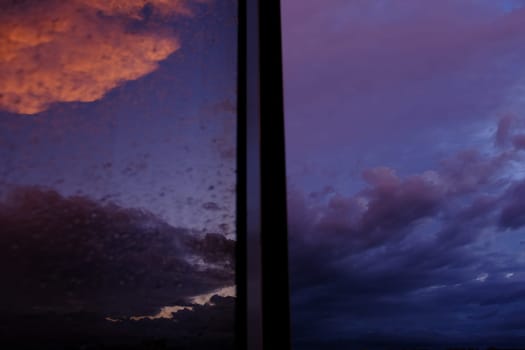 Dawn sky with colorfull clouds. Sunset landscape through the window with reflection on it.