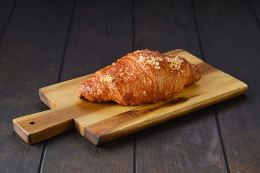 Classic croissant on wooden serving board.