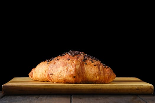 Croissant with chockolate icing on wooden serving board
