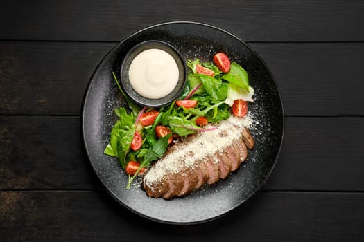 Top view of sliced beefsteak with parmesan and fresh vegetables