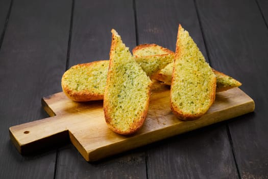 Crispy toasted garlic bread on wooden serving board