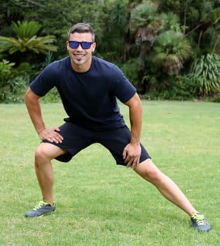 Handsome young man doing stretching exercises outdoors