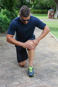 Handsome young athlectic man inspecting his sore knee