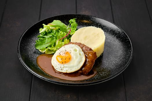 Beef cutlet with fried egg, mashed potato and fresh salad on a plate