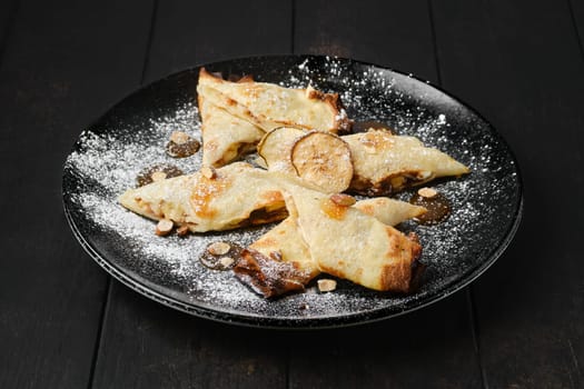Thin pancakes stuffed with pear, almond and caramel on a plate