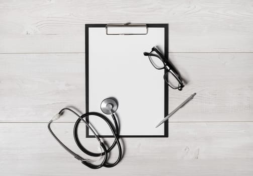 Doctor's medical supplies. Blank clipboard, stethoscope, glasses and pen. Flat lay.