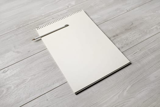 Photo of blank notepad and pencil on light wooden background. Responsive design template.